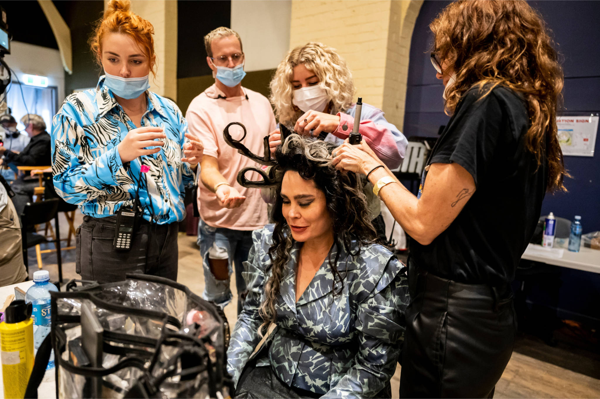 A photo of 4 hair and makeup artists working on an actor