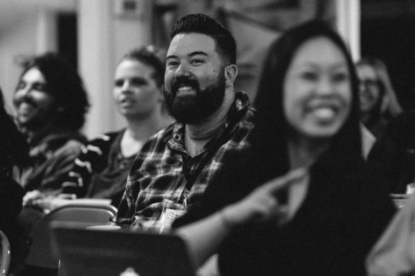 A black and white photo of men and women sitting in rows and smiling