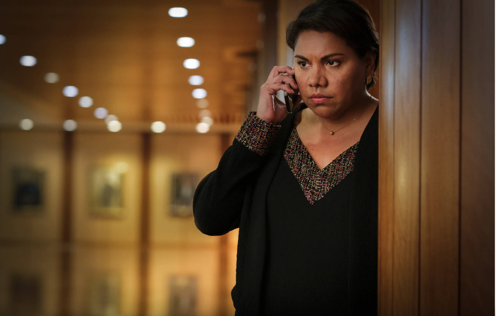 Deborah Mailman plays Alex Irving in TOTAL CONTROL. In the image she is looking series while on a phone call in a corridor