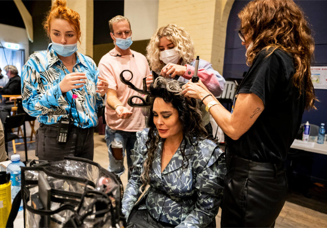 A photo of 4 hair and makeup artists working on an actor