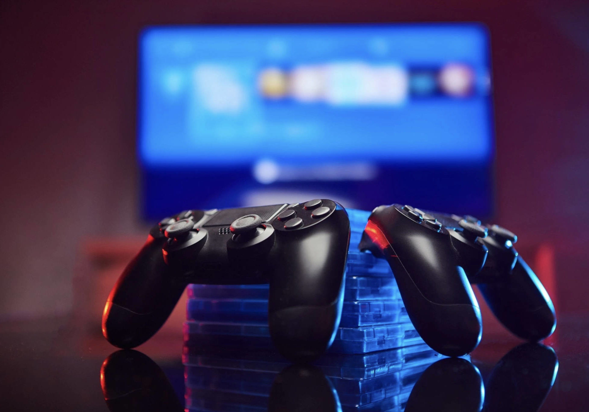 Two computer game controllers stacked against games with a TV in the background