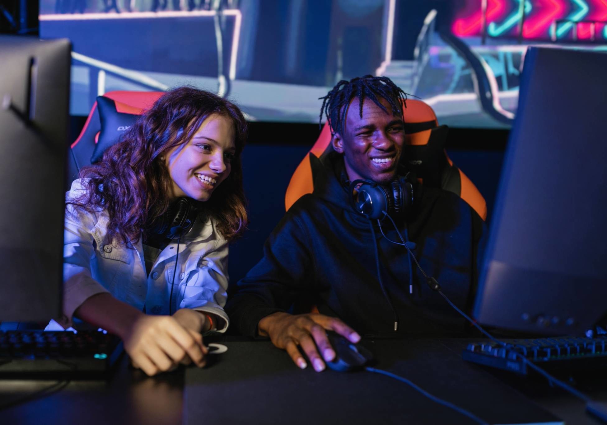 A photo of two gamers smiling while looking at a computer screen